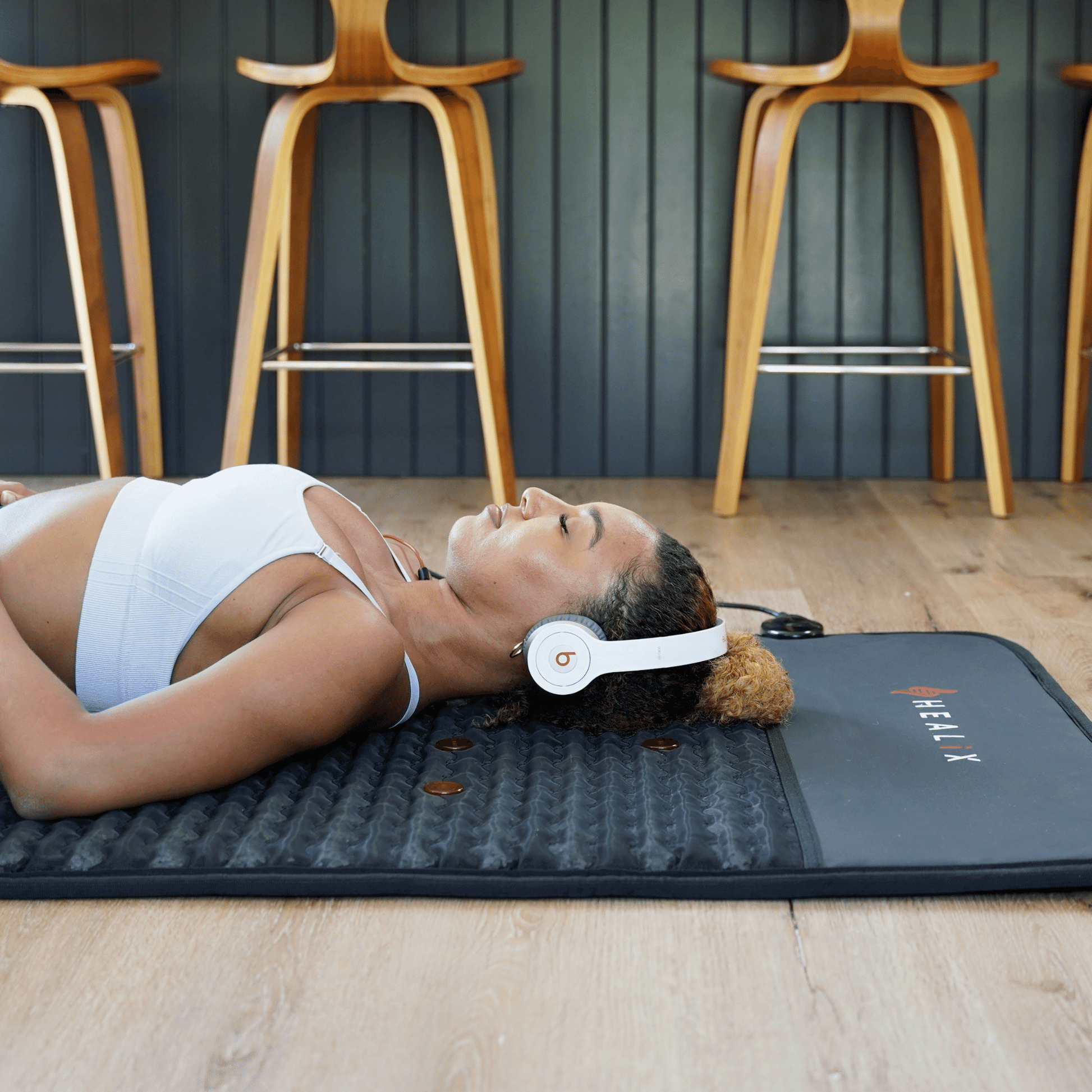 Person lying on a mat with headphones, in a gym setting.